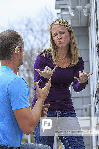 Homeowner communicating with home repairman in American Sign Language  saying 'Spring' and 'Not now'