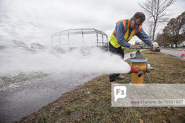 Water department technician opening fire hydrant to flush water pipes