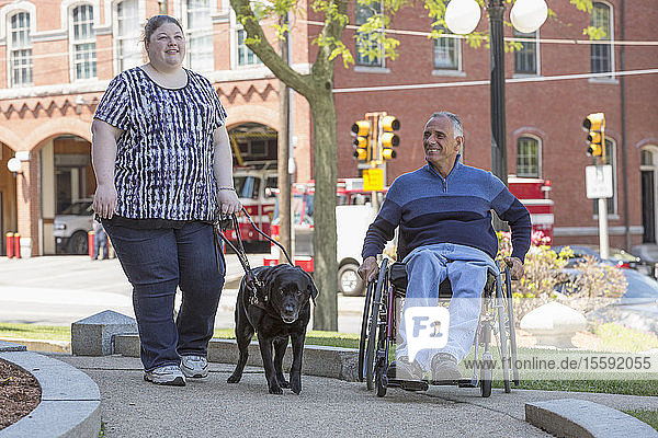 Ein Mann mit einer Rückenmarksverletzung und seine blinde Tochter mit einem Diensthund