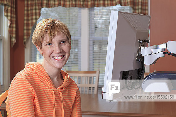 Porträt einer jungen Frau mit Sehbehinderung  die an ihrer Schreibtischlupe sitzt