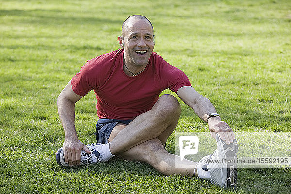 Hispanischer Mann  der in einem Park trainiert und lächelt