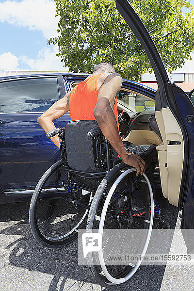 Mann mit spinaler Meningitis im Rollstuhl beim Einsteigen in ein Auto