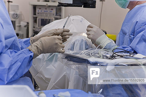 Chirurgische Technikerin gibt Antibiotikum an Arzt während Kataraktoperation weiter