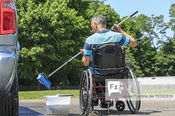 Man with a Spinal Cord Injury in wheelchair washing his accessible car