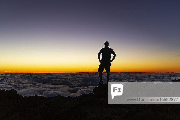 Silhouettierter Mann steht auf einem Felsen über den Wolken bei Sonnenuntergang  Haleakala; Maui  Hawaii  Vereinigte Staaten von Amerika
