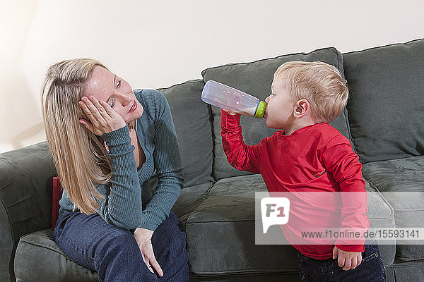 Frau  die das Wort Bett in amerikanischer Zeichensprache gebärdet  während ihr Sohn Milch trinkt