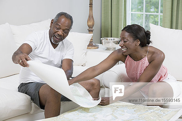 Ehepaar mittleren Alters sitzt auf einer Couch und studiert eine Karte von Segelbootrennen
