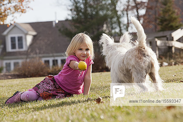 Mädchen spielt Ball mit Haustier Terrier