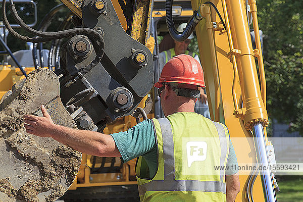 Construction foreman guiding excavator operator
