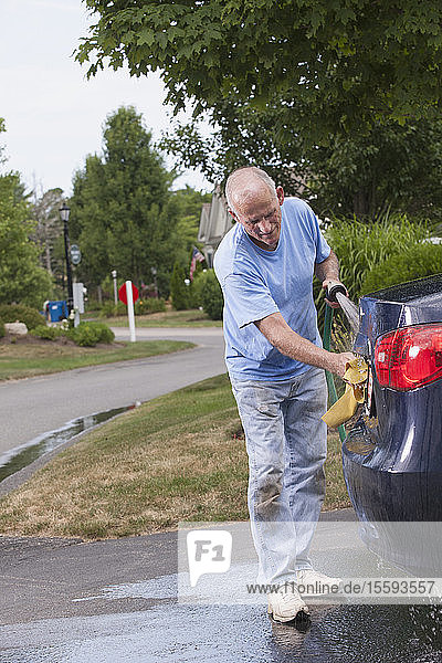 Älterer Mann wäscht sein Auto zu Hause