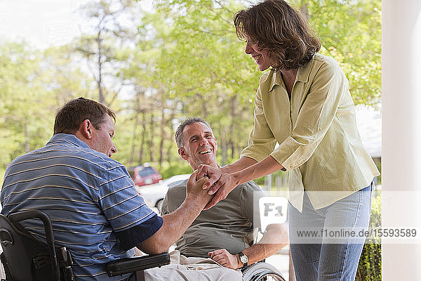 Two men in wheelchairs with Spinal Cord Injuries greeting a friend