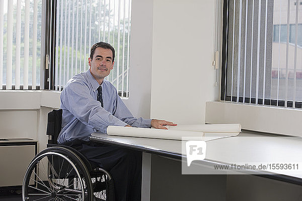 Businessman with spinal cord injury holding a blueprint
