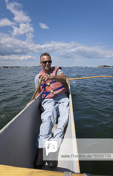 Mann mit Rückenmarksverletzung paddelt mit Auslegerkanu auf dem Meer