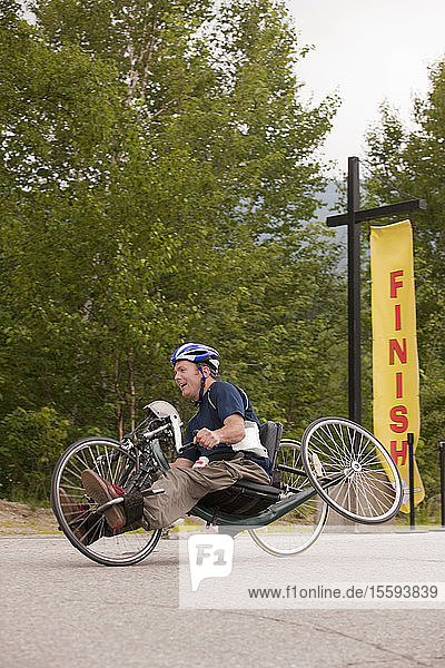 Mann mit Querschnittslähmung auf der Ziellinie eines Handbike-Rennens