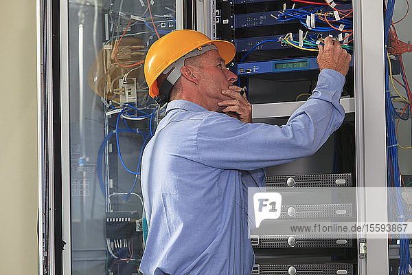 Electrical engineer working with switches and servers in broadband communication hub of electric power plant