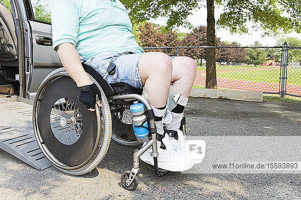 Mann mit Muskeldystrophie im Rollstuhl beim Aussteigen aus einem zugänglichen Lieferwagen