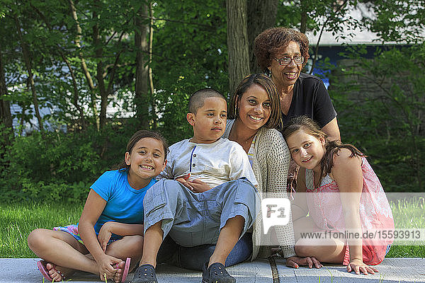 Glückliche hispanische Familie mit autistischem Jungen sitzt zusammen in einem Park
