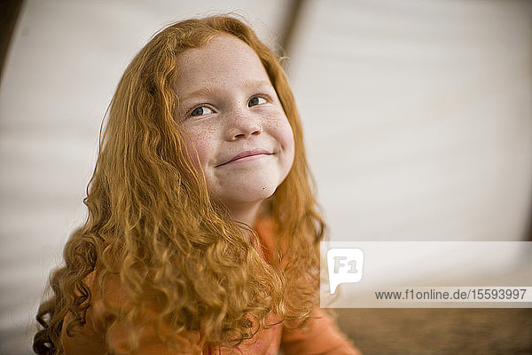 Smiling young girl with long red hair and freckles
