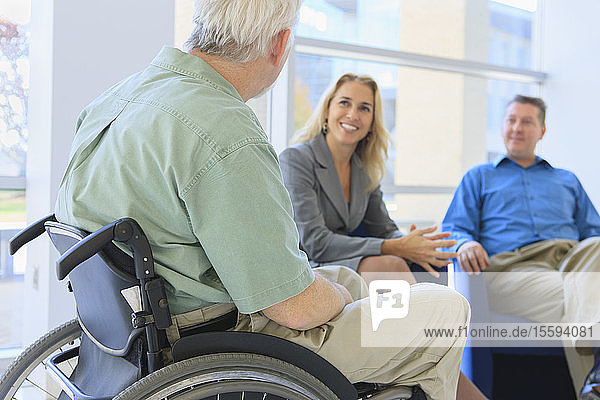 Mann mit Muskeldystrophie im Rollstuhl im Gespräch mit Freunden