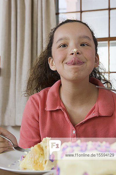 Hispanisches Mädchen  das versucht  die Kuchenglasur auf ihrer Nase abzulecken