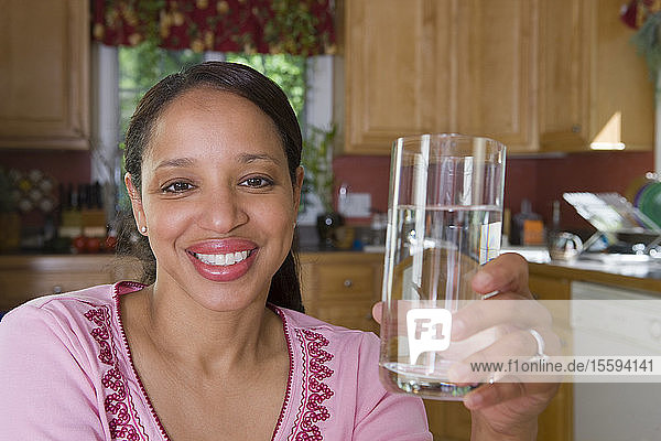 Hispanic woman holding a glass of water and smiling