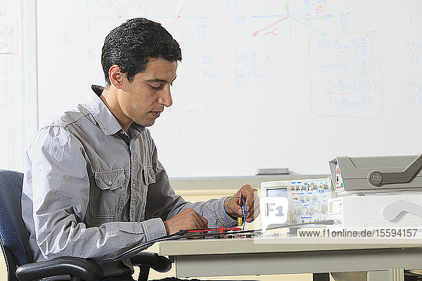 Ingenieurstudent beim Einsetzen eines Bauteils in ein Prototyping-Breadboard für ein Experiment im Elektroniklabor
