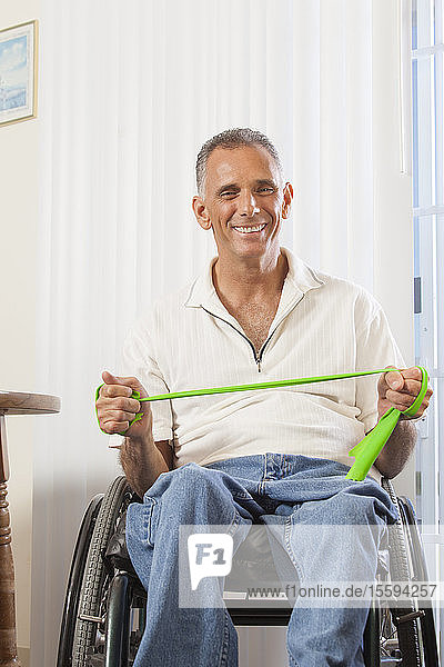 Mann mit Rückenmarksverletzung im Rollstuhl bei der Verwendung von Geräten zur Stärkung von Händen und Armen