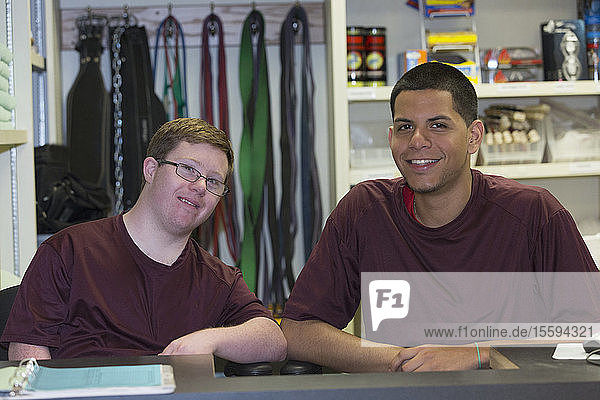 Junger Mann mit Down-Syndrom arbeitet mit seinem Betreuer in der Ausgabestelle für Sportgeräte an der Hochschule