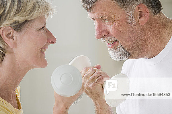 Close-up of a senior couple holding hand weights and smiling