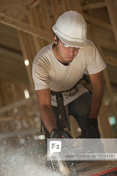 Zimmermann bei der Arbeit mit einer Kreissäge an einer Dachplatte in einem im Bau befindlichen Haus