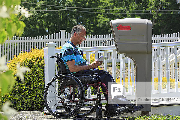 Mann mit einer Rückenmarksverletzung im Rollstuhl holt seine Post ab