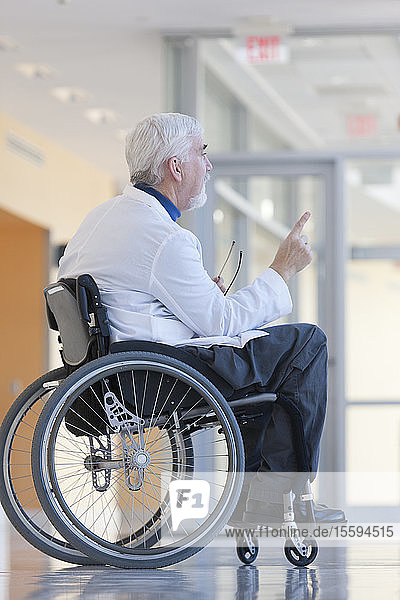 Arzt mit Muskeldystrophie im Rollstuhl auf dem Krankenhausflur