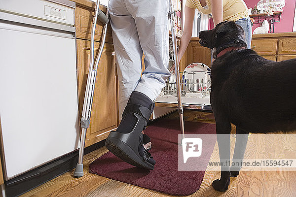 Low section view of a disabled woman standing in the kitchen near a dog