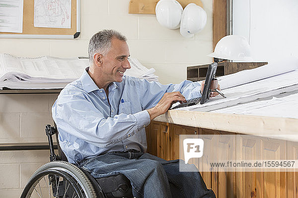 Project engineer using tablet to check job site plans  while in a wheelchair with a Spinal Cord Injury