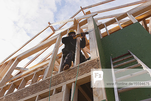 Zimmermann bei der Arbeit mit einer Säbelsäge an einem im Bau befindlichen Haus