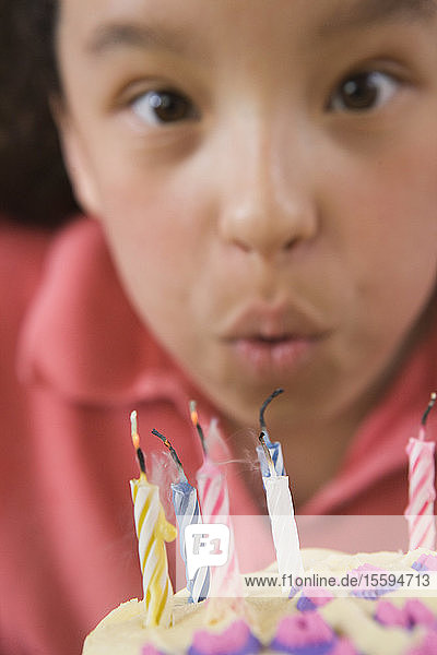 Hispanic girl blowing out candles on a birthday cake