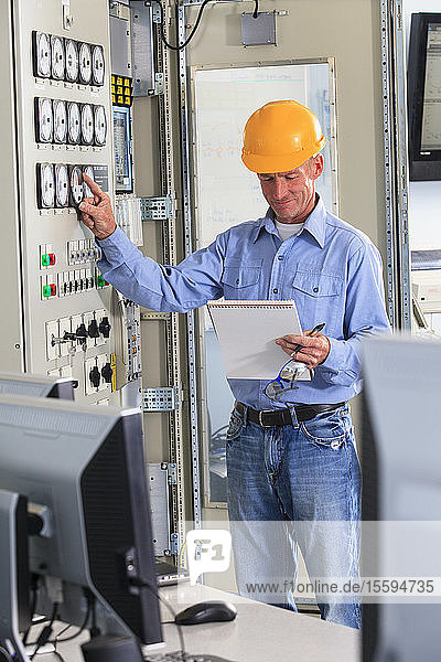 Electrical engineer inspecting power plant controls in central operations room of power plant
