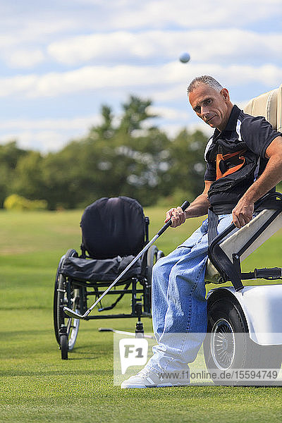 Mann mit Querschnittslähmung in einem adaptiven Wagen zum Golfspielen