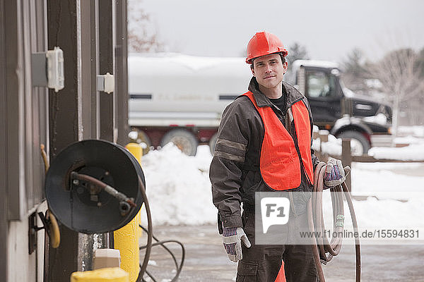 Transportation engineer unrolling hose at an industrial garage in winter