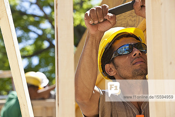 Zimmermann bei der Arbeit mit einem Hammer auf einer Baustelle
