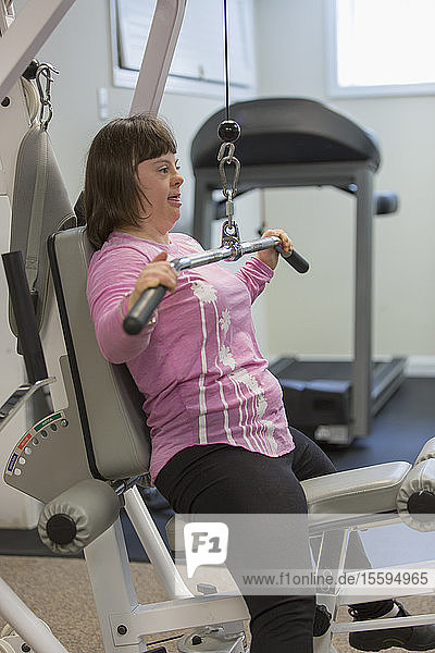 Girl with Down Syndrome working out on an exercise machine