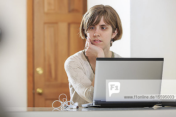 Blinde Frau  die mit Hilfe von Hilfsmitteln an ihrem Computer zuhört