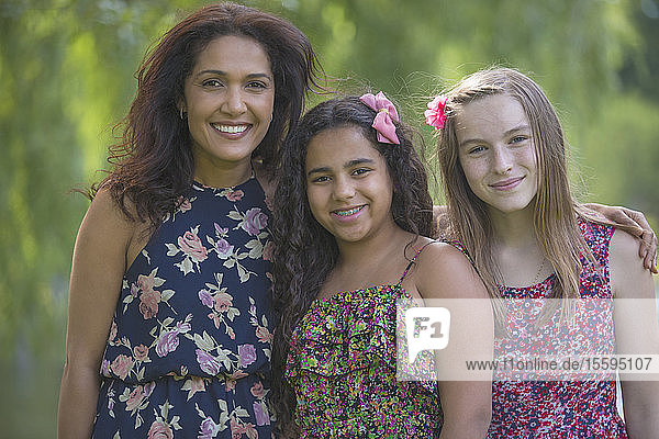 Porträt einer glücklichen hispanischen Mutter und zweier Teenager-Töchter mit Zahnspange im Park