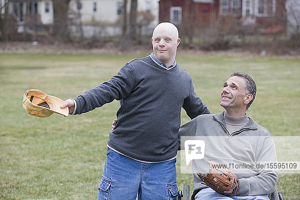 Behinderter Mann lächelt mit seinem Sohn mit Down-Syndrom