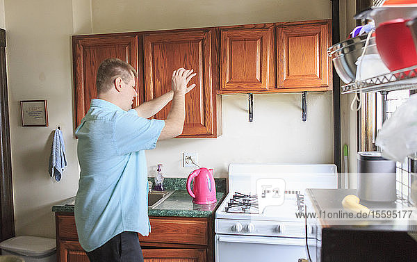 Mann mit Sehbehinderung arbeitet in der Küche seines Hauses