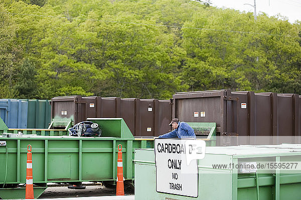 Techniker beim Sortieren von Karton in der Cardboard Only Recyclingpresse  die mit einem Container verbunden ist