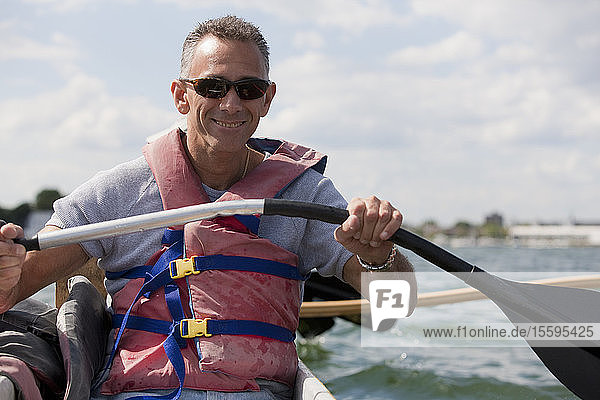 Mann mit Rückenmarksverletzung paddelt mit Auslegerkanu auf dem Meer