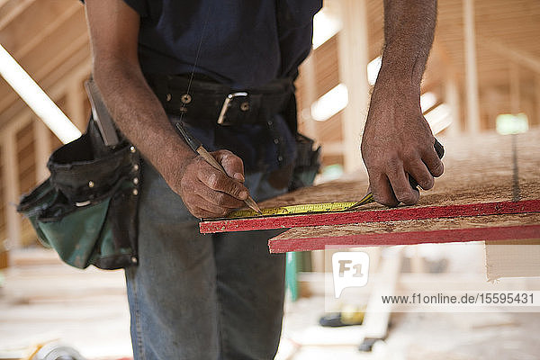 Spanischer Zimmermann beim Ausmessen einer Dachplatte eines im Bau befindlichen Hauses