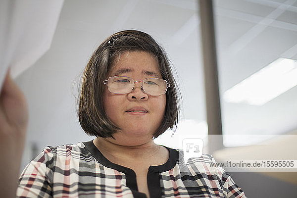 Asiatische Frau mit einer Lernbehinderung arbeitet an einem Kopiergerät