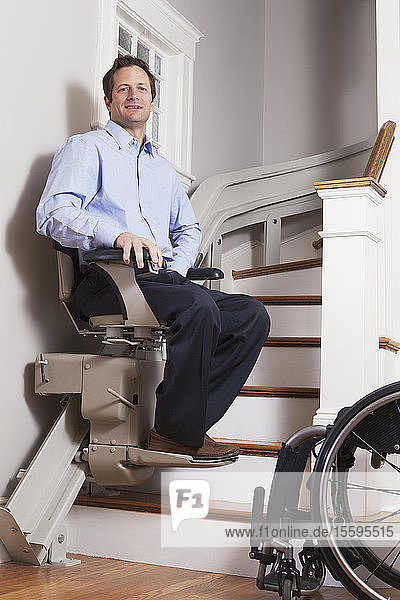 Mann mit Rückenmarksverletzung fährt mit seinem motorisierten Treppenlift nach oben
